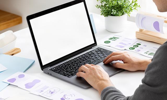 Tekstschrijver werkt aan een websitepakket op een laptop in een lichte creatieve werkruimte